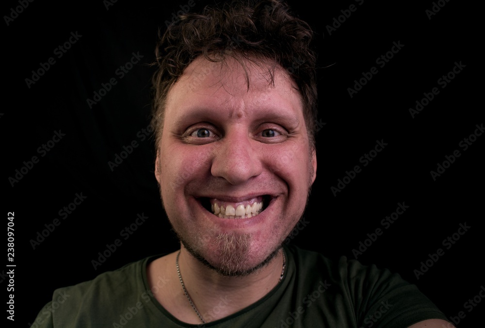 Fototapeta premium Joyfully laughing young man. Scoffs his teeth. Mad look into the camera.