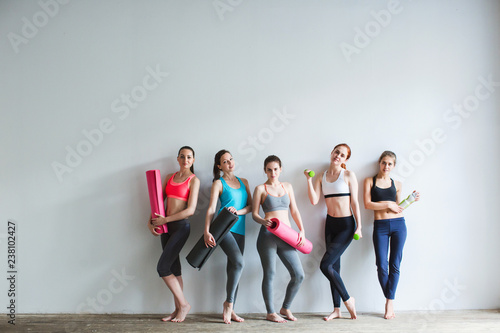 Group of female friends in sportswear together standing in a gym after yoga.