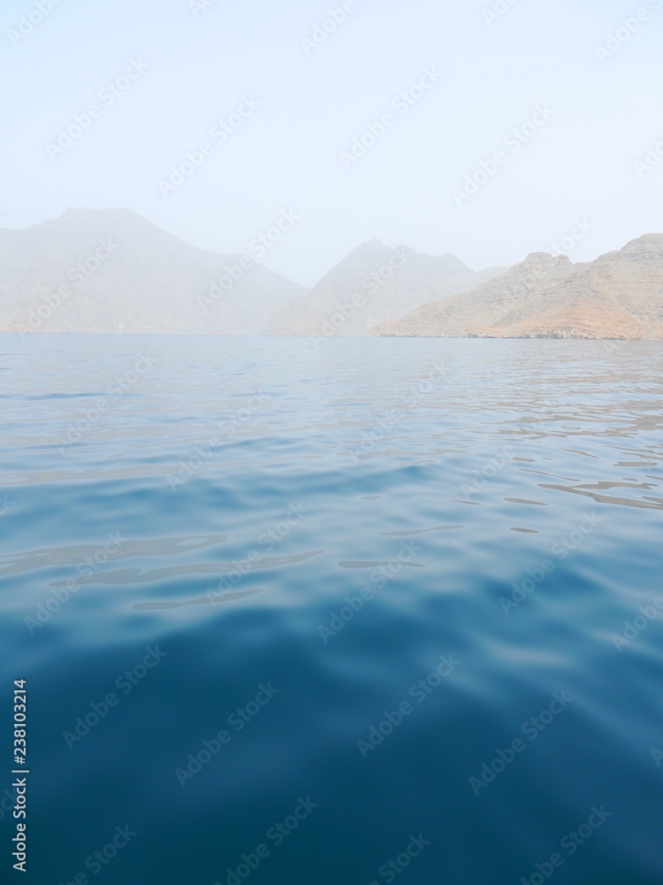 blurry ambiance of a wide blue ocean and massive fjords mountains, Musadam, Khasab, Oman, Middle East blurry ambiance of a wide blue ocean and massive fjords mountains, Musadam, Khasab, Oman, Middle East