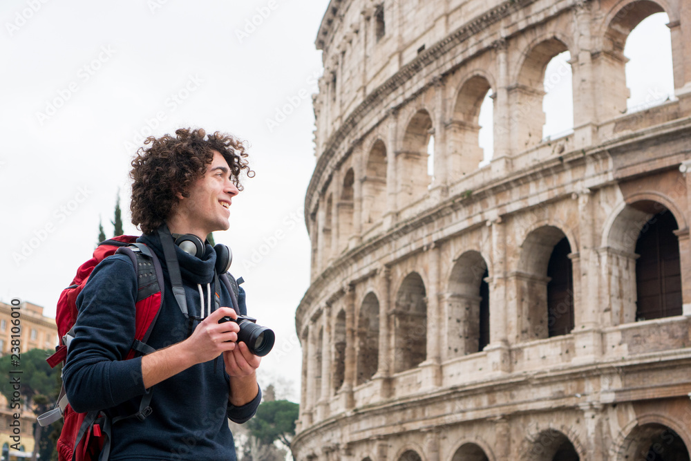 Handsome young tourist man with a camera and backpack taking pictures