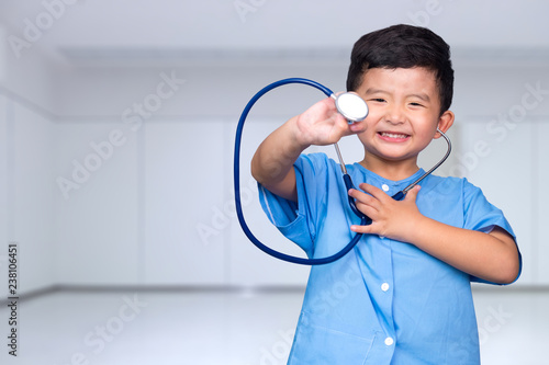 Smiling Asian kid in blue medical uniform holding stethoscope looking at camera, healthy concept.