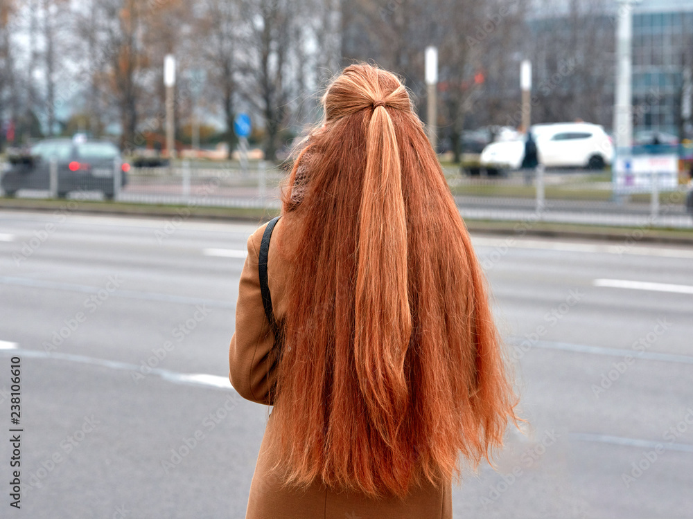 Beautiful red haired girl wearing coat from behind on the street. Female  with luxurious well-groomed hairstyle. Shiny healthy waist long hair. Woman  nurture lushy red hair. Photos | Adobe Stock