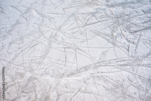 Floor background of a frozen ice rink with skate marks, with white snow during the winter.