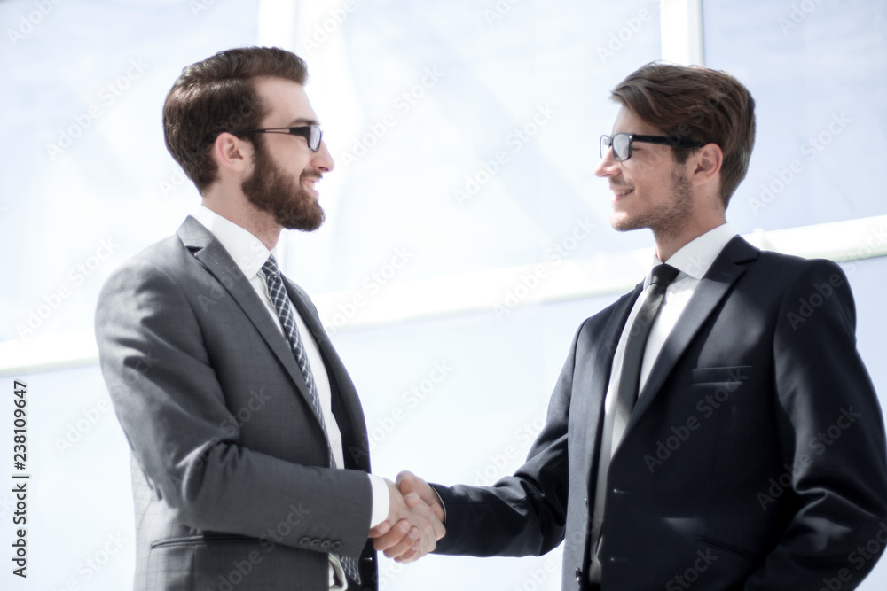 handshake business partners in a bright office handshake business partners in a bright office