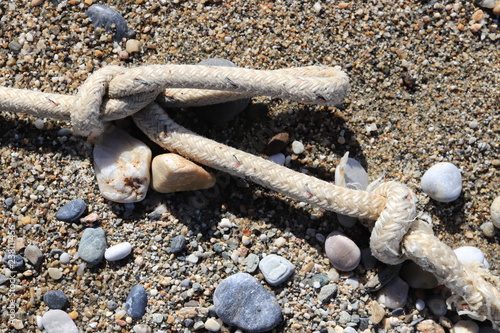 Fototapeta Naklejka Na Ścianę i Meble -  Rope with stone on sand beach