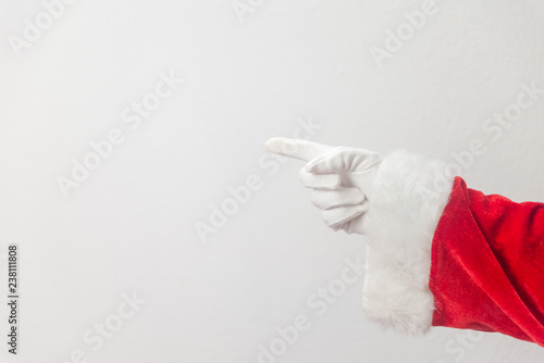 Santa Claus pointing finger show direction on a light texture background. Seasonal closeup of holiday excitement and hope. photo