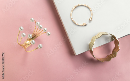 Fotótapéta Golden bracelet with pearls and golden zigzag shape cuff on pink and white paper