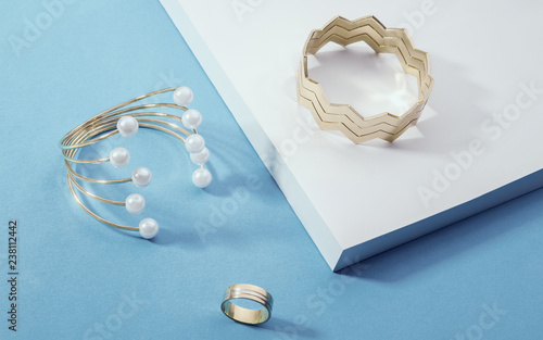 Shiny Golden bracelets and a ring on white corner on blue paper background