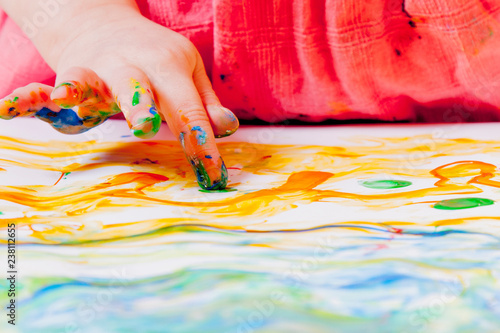 Art, creativity, childhood concept. Little cute child girl painting with fingers.