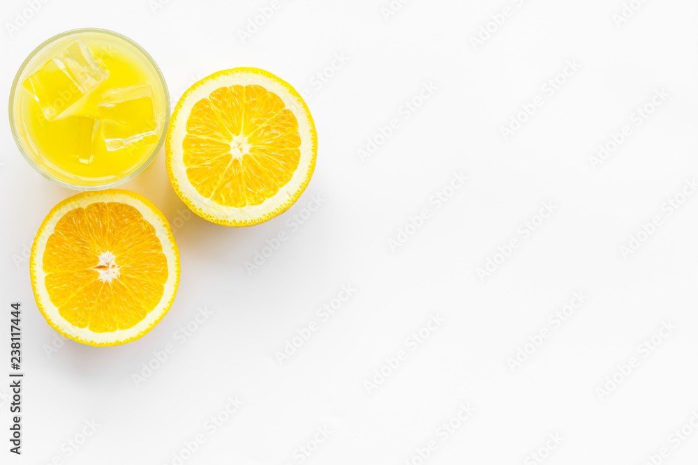 Glass of cold orange juice near halfs of fresh oranges on white background top view space for text