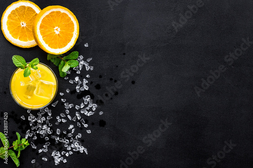 Orange juice and citrus cocktails. Juice in glass near cut orange and lemon, crushed ice, green mint on black background top view space for text
