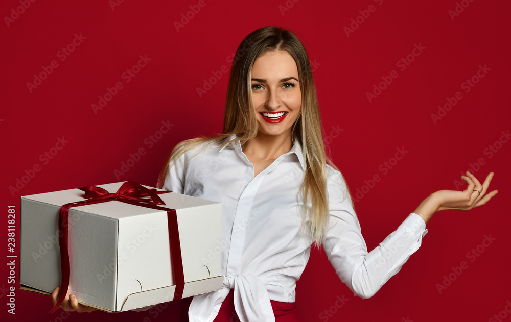 Young blonde woman hold white box gift present smiling pointing hand finger at the corner Young blonde woman hold white box gift present smiling pointing hand finger at the corner