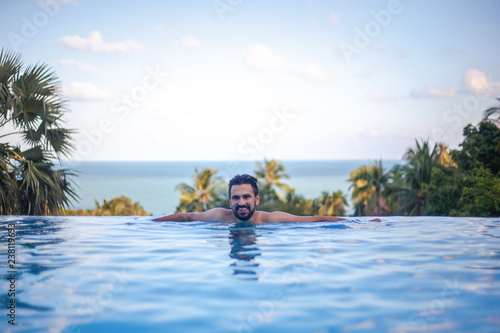 Young attractive sexy Hispanic male, mixed race with beard in the pool, leisure and travel in warm countries © olezzo
