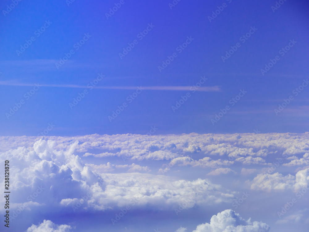 Naklejka premium Sea of clouds as seen from an airplane with horizon, deep blue sky and a white horizontal track of flight