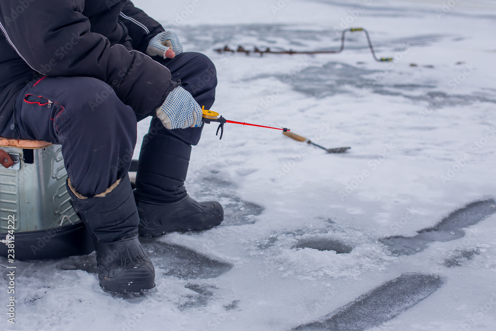 Close-up hand of fisherman catches fish on a winter fishing rod on