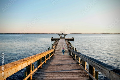 A little girl in a bicycle helmet on the pier seems intimidated by the vast size of the Neuse River estuary at a park in Arapahoe North Carolina. photo