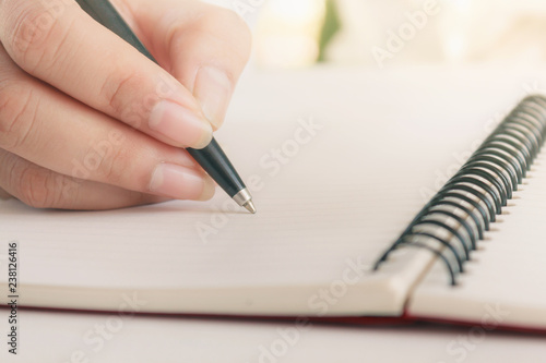 Woman hand with pen writing on notebook. Blank copy space.