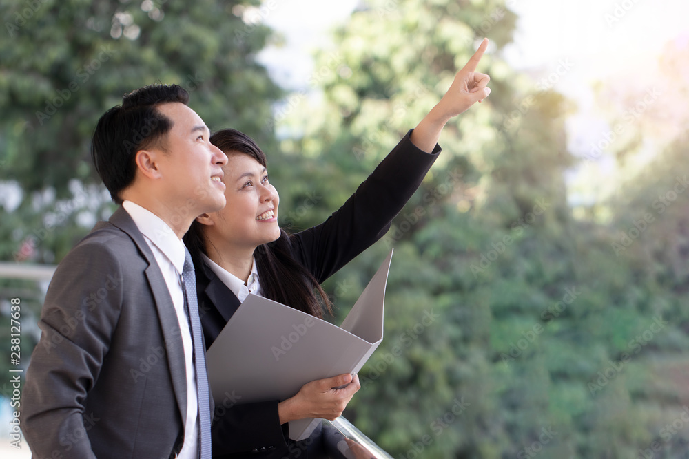 Businessman and secretary planning and creating new projects. They have a bright smile to see goal and successful in the future. Soft focus and blur.
