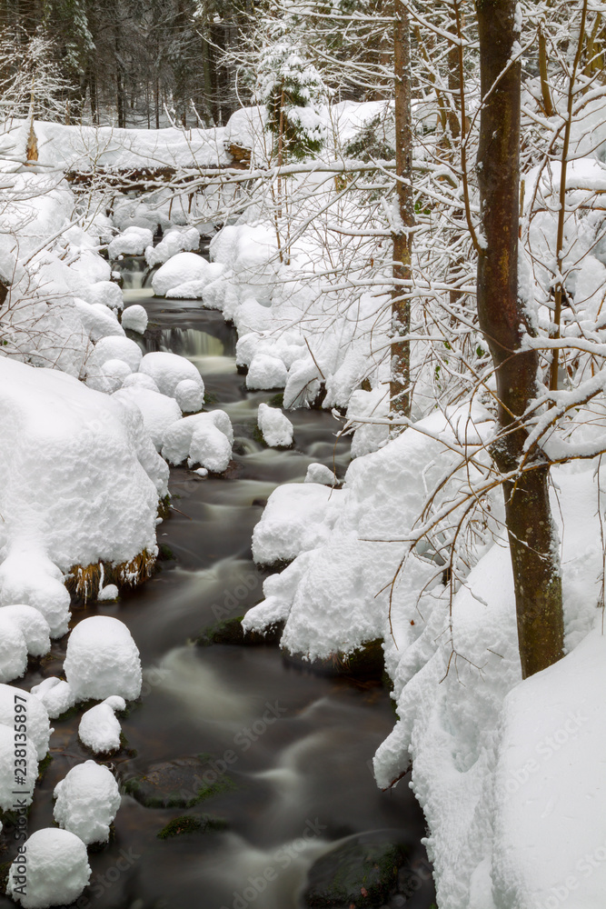 Long exposure of the Kleine Ohe, a small creek flowing through the snowy forest in the Bavarian Forest National Park in Bavaria, Germany. Long exposure of the Kleine Ohe, a small creek flowing through the snowy forest in the Bavarian Forest National Park in Bavaria, Germany.