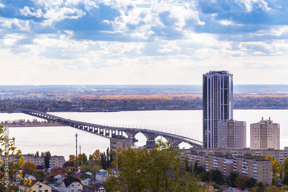 Obraz premium Travel to Russia. Landmark of the Volga region, the bridge over the Volga River between the city of Saratov and Engels near the skyscraper and the city beach. View from Sokolovaya Mountain.