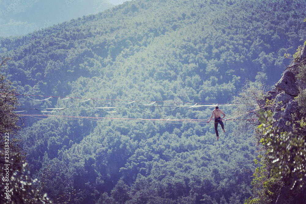 Highliner on a rope. Highline on a background of mountains. Extreme sport on the nature. Balancing on the sling. Equilibrium at altitude. Highliner on a rope. Highline on a background of mountains. Extreme sport on the nature. Balancing on the sling. Equilibrium at altitude.