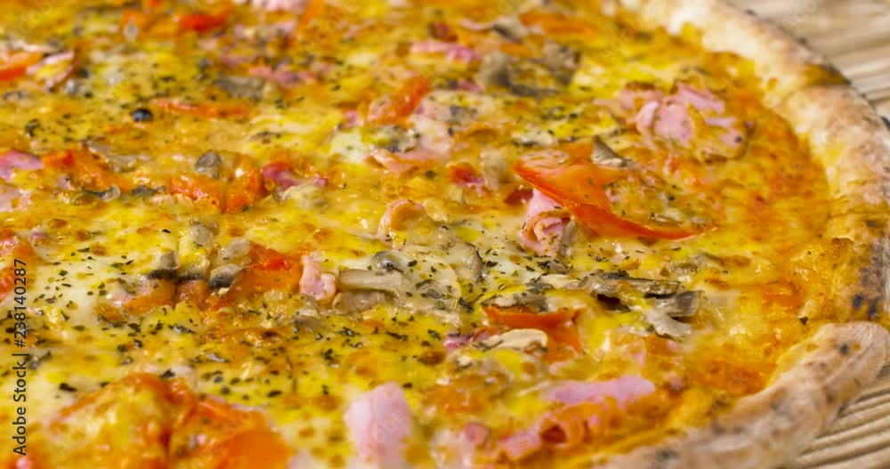 Nice yummy fresh hot pizza rotating on wood cooking surface. Close up. Nice yummy fresh hot pizza rotating on wood cooking surface. Close up.