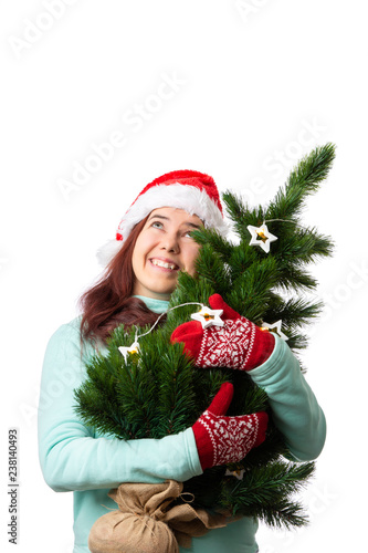 Photo of woman in Santa's cap with Christmas tree in hand