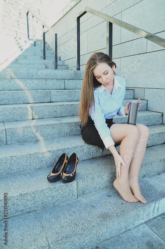 Business woman, during the break, sat down on the steps to stretch her legs, after a hard day's work
