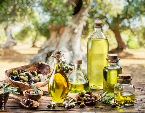 Oliwa z oliwek i jagody są na drewnianym stole pod drzewem oliwnym.