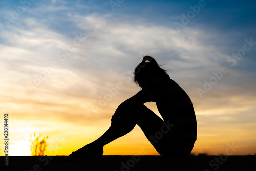 Silhouette woman sitting sad in the sunset.