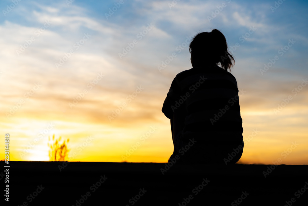 Silhouette woman sitting sad in the sunset.