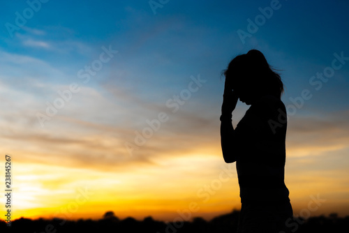 Silhouette woman standing sad in the sunset.