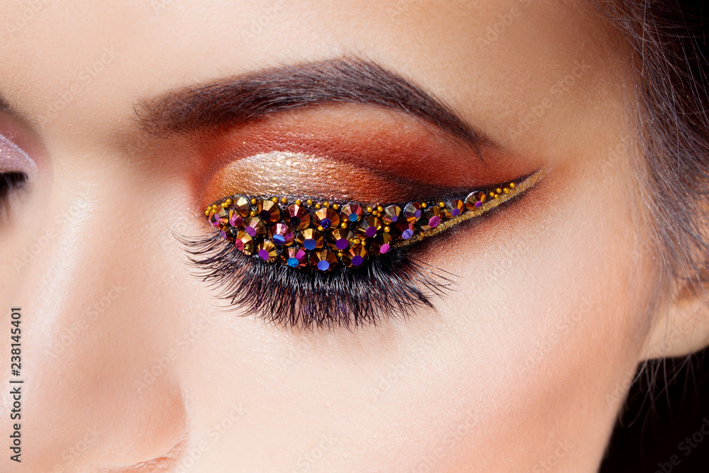 Amazing Bright eye makeup with a arrow with rhinestones. and gold tones, colored eyeshadow Stock Photo Adobe Stock