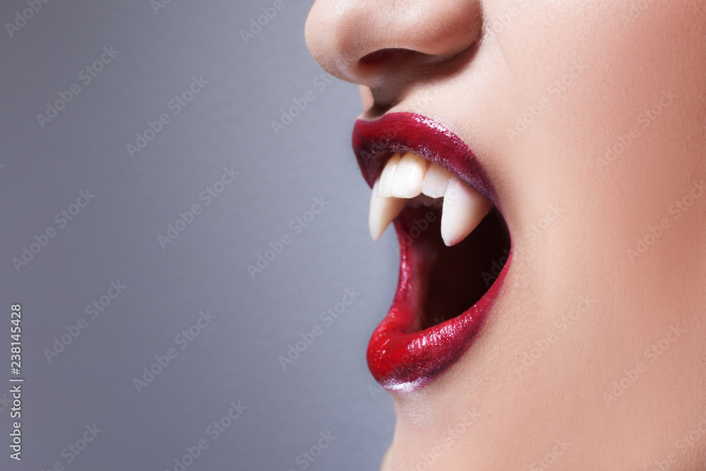 Sexy vampire. Women's lips with red lipstick. Screaming mouth with vampire  fangs Stock Photo | Adobe Stock