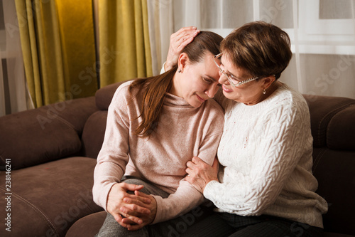Foto senior mother consoles, comforting sad adult grown daughter sitting at sofa at home