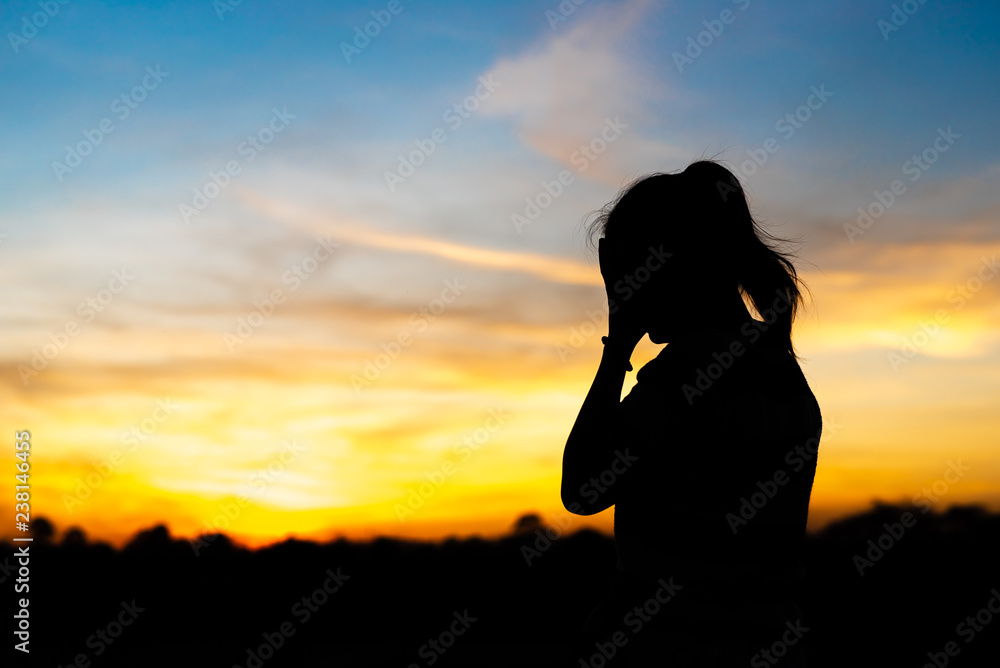 Silhouette woman standing sad in the sunset.