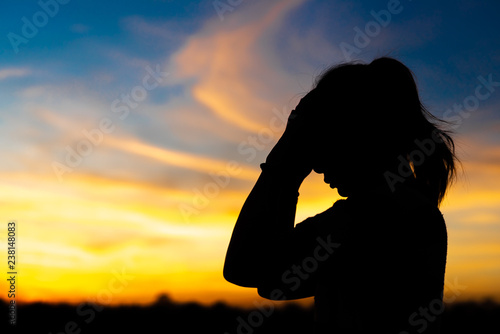 Silhouette woman standing sad in the sunset. © patcharee11