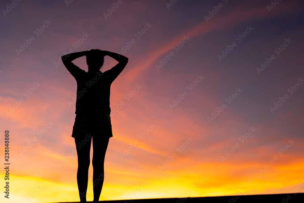 Silhouette woman standing sad in the sunset.