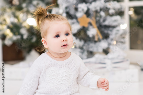 Baby girl on a background of Christmas trees, lights, Christmas balls and gift boxes