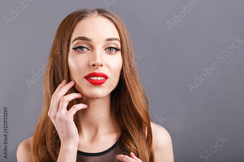 Attractive long haired woman with red lips wearing black dress standing on the gray background, New Year, Christmas, holidays, souvenirs, gifts, shopping, discounts, shops, make-up, hairstyle