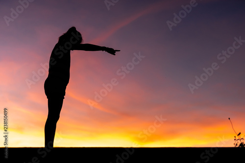 Silhouette woman standing sad in the sunset.