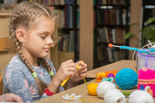 The girl knits embroidery in the school library photo