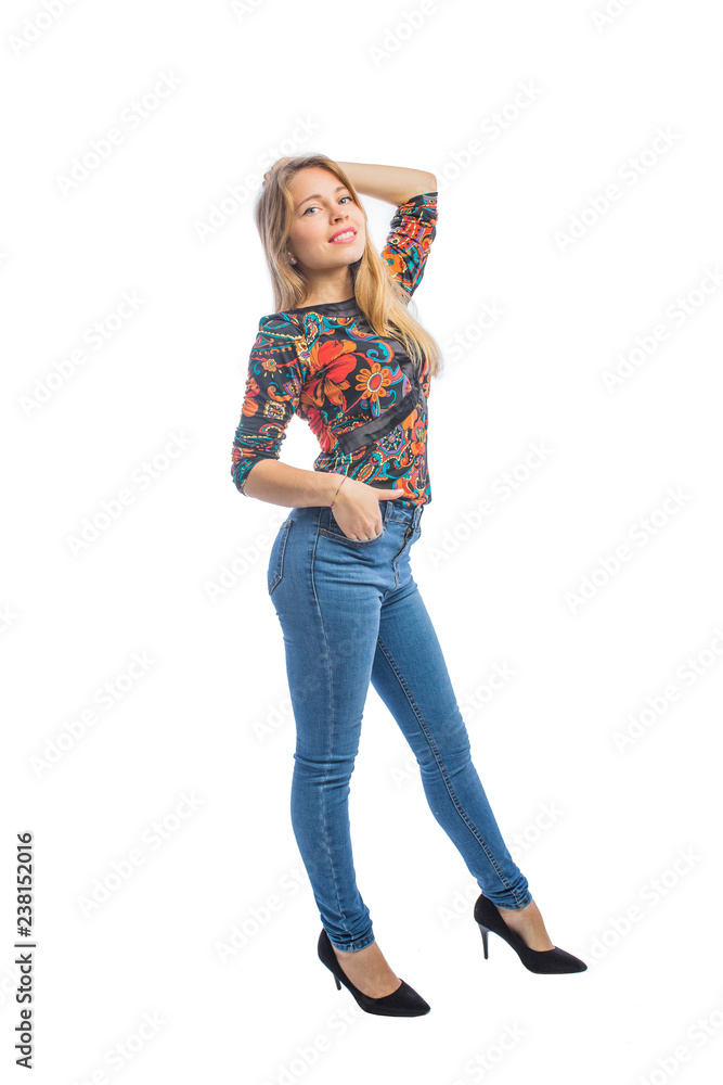 Charming young woman with long blond hair in jeans, a blouse and shoes posing in profile Charming young woman with long blond hair in jeans, a blouse and shoes posing in profile