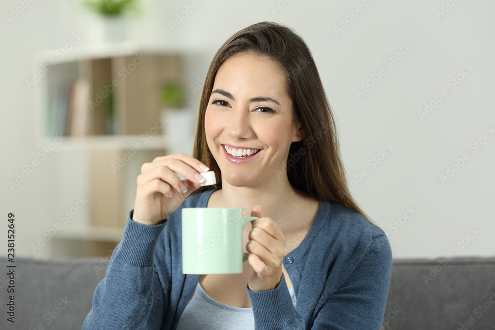 Happy woman throwing sugar into mug looking at you Happy woman throwing sugar into mug looking at you