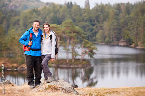 Young adult couple standing on a rock beside a lake in countryside, smiling to camera, full length © Monkey Business