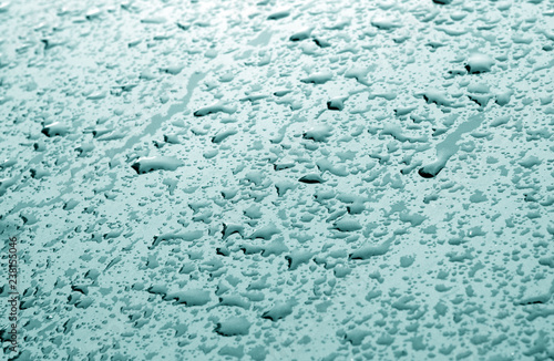 Water drops on car surface in cyan tone.