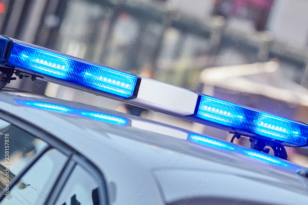 Fototapeta premium Police car with blue lights on the crime scene in traffic / urban environment.