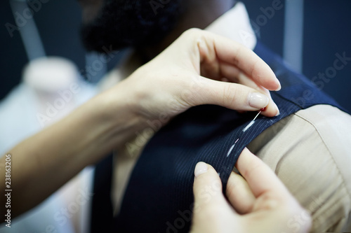 Fotografie Close-up of unrecognizable tailor using sewing pins to fix fabric while correcti