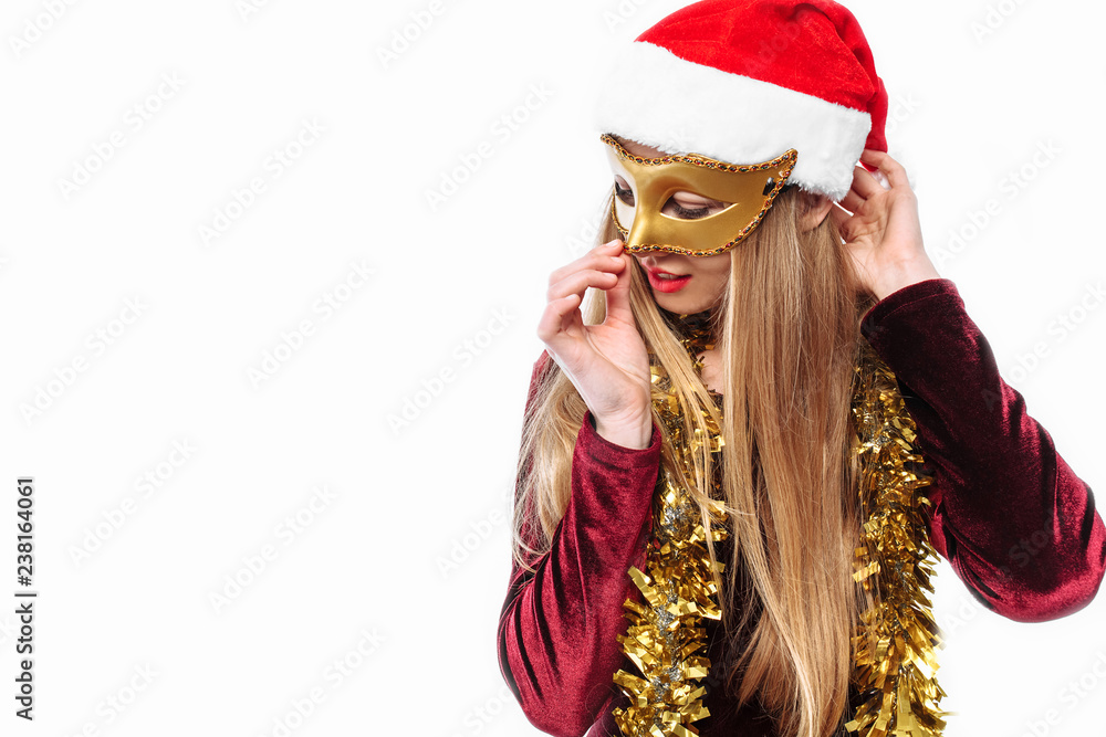 Cheerful woman in santa hat and carnival mask on her face, celebrating the new year.