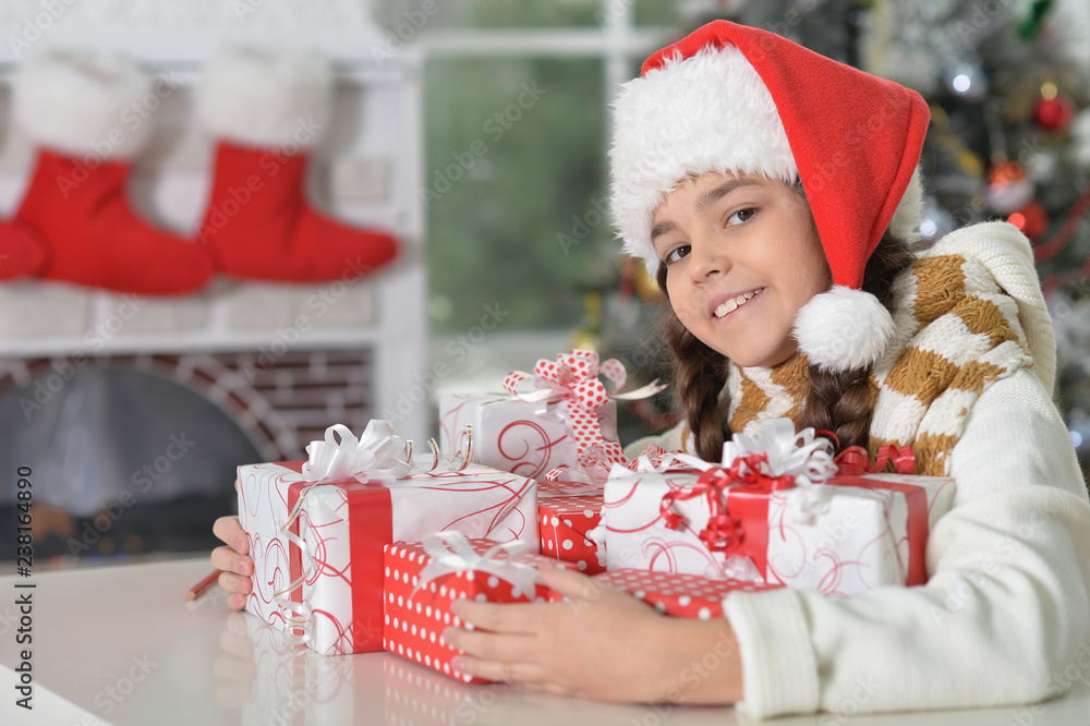 Cute little girl in Santa hat with gifts for Christmas at home Cute little girl in Santa hat with gifts for Christmas at home